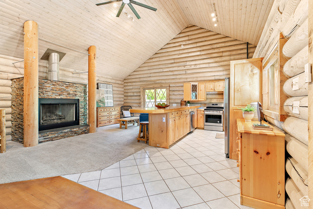Kitchen with wooden counters, rustic walls, stainless steel appliances, and light brown cabinetry