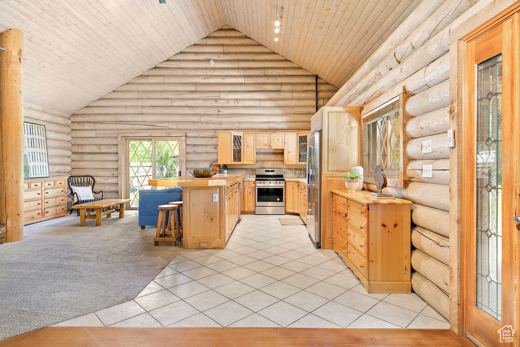 Kitchen featuring light brown cabinets, log walls, wood ceiling, high vaulted ceiling, and stainless steel appliances