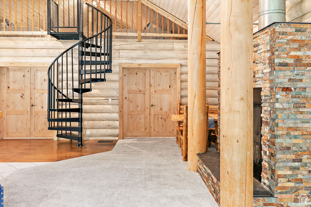 Stairway with carpet, rustic walls, and high vaulted ceiling