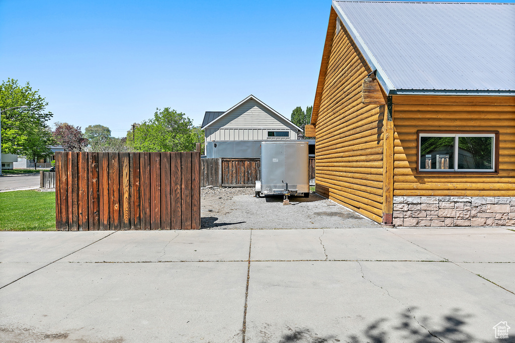 View of side of property featuring metal roof and fence