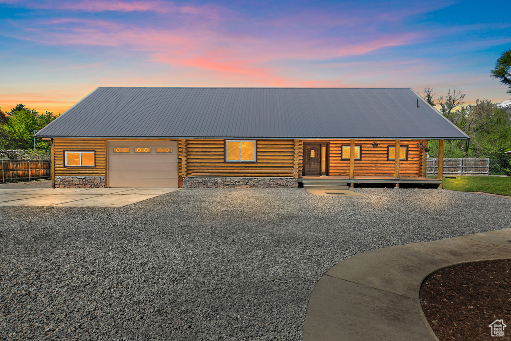 View of front of home featuring metal roof, a garage, fence, and log siding