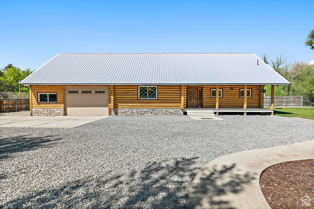 Cabin featuring log exterior, concrete driveway, fence, and a garage