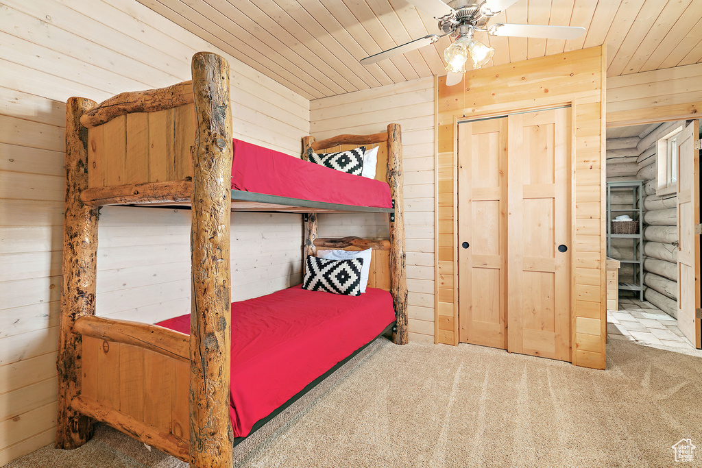 Bedroom featuring carpet floors, wooden walls, ceiling fan, and wooden ceiling