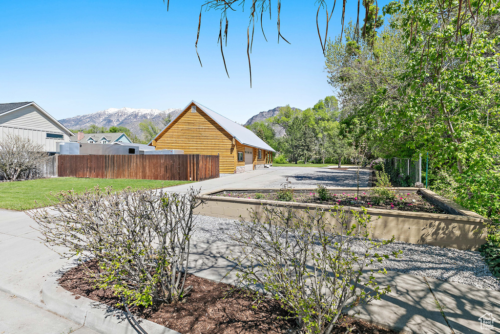 View of side of home featuring a mountain view, fence, and log siding