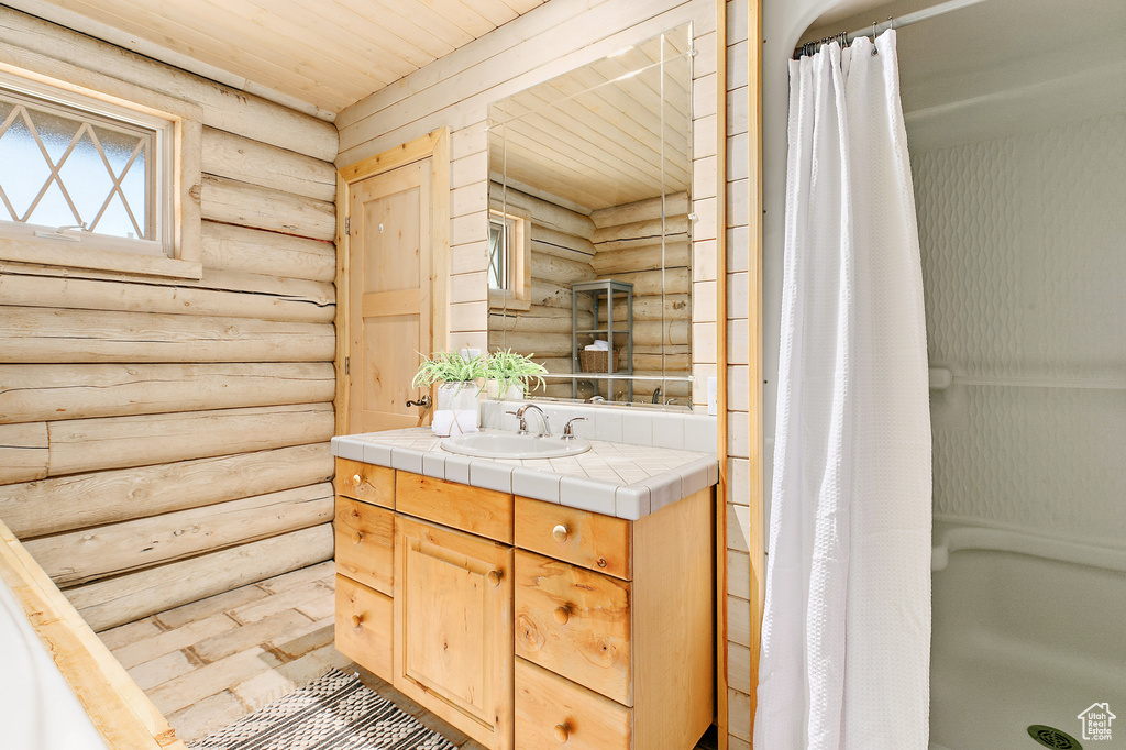 Bathroom with vanity, a shower with shower curtain, wood ceiling, and log walls
