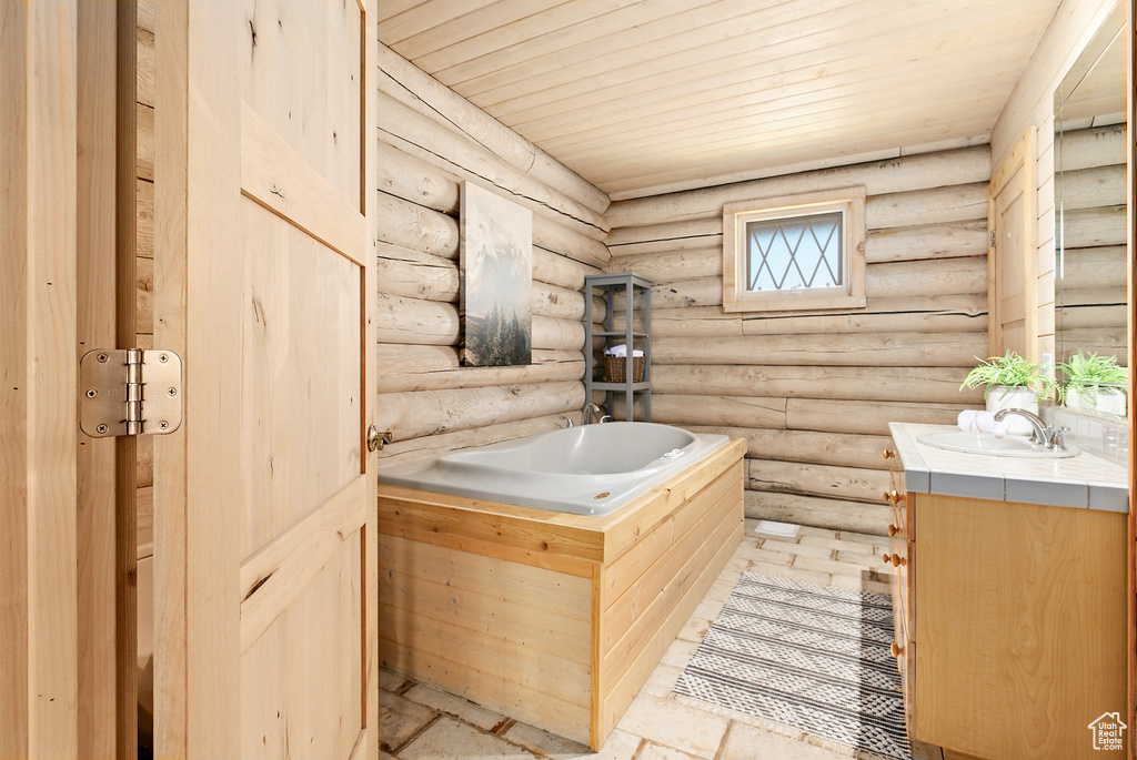 Bathroom with wood ceiling, vanity, and a tub to relax in