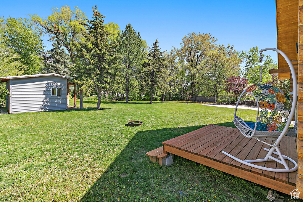 View of yard with an outbuilding, a wooden deck, and fence