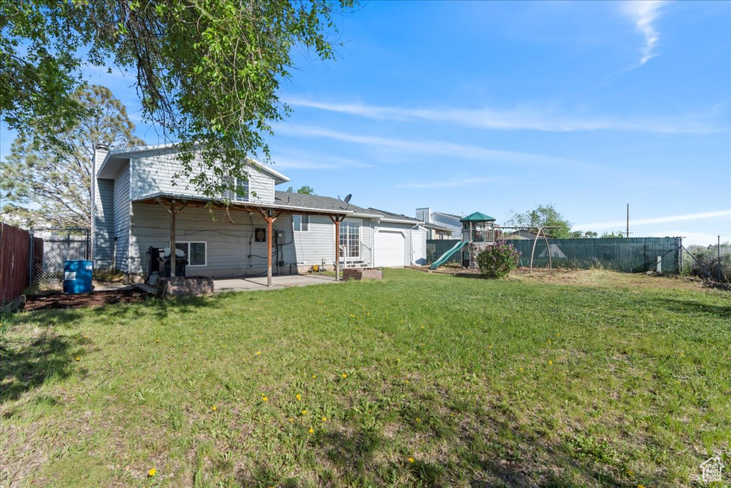 View of yard featuring a playground, a patio area, and an attached garage