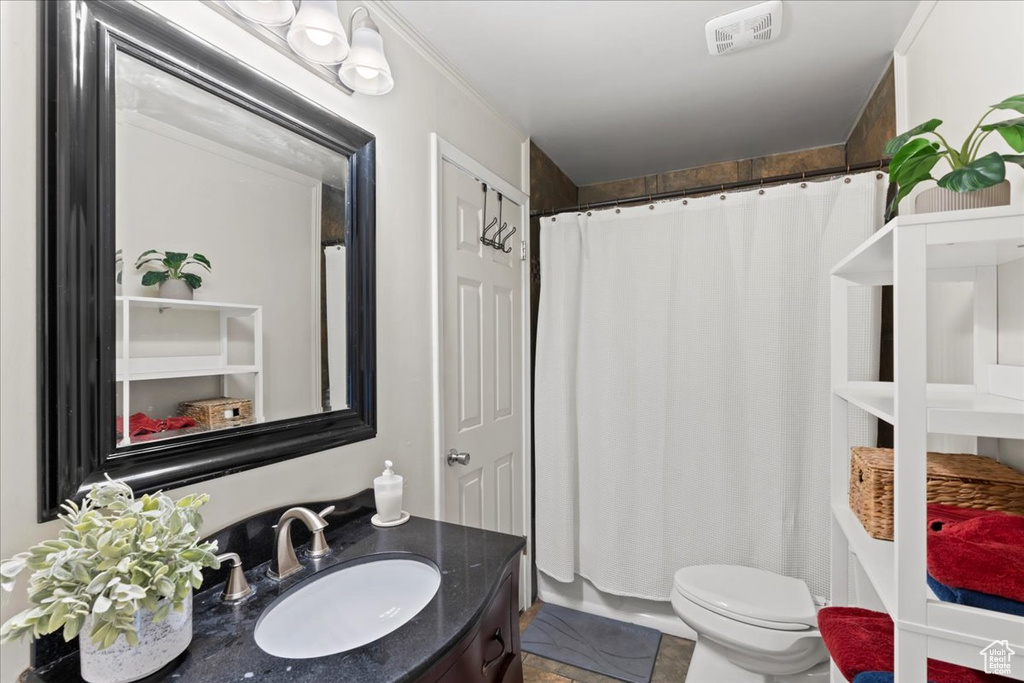 Bathroom featuring a shower with curtain, toilet, and vanity