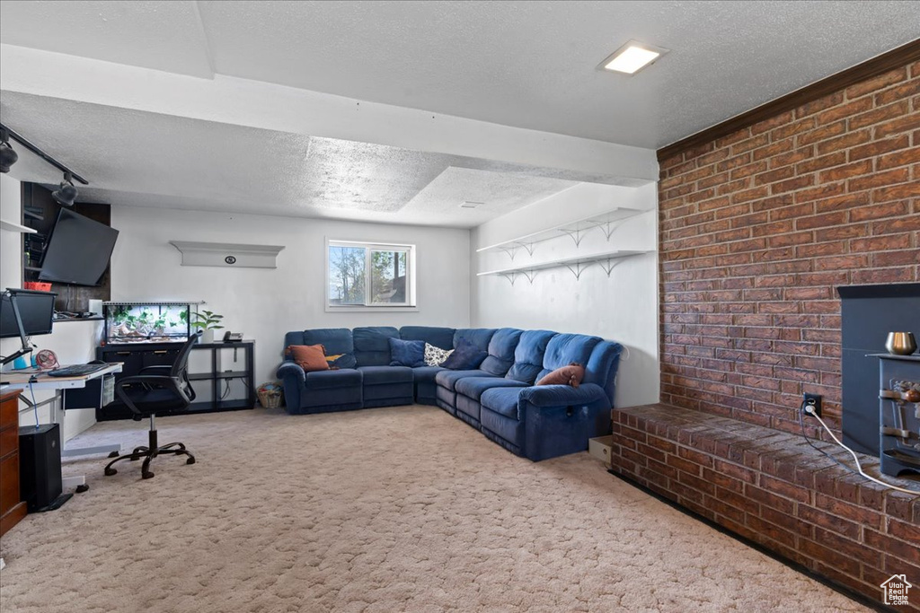 Living area featuring carpet floors, a desk, a textured ceiling, and brick wall