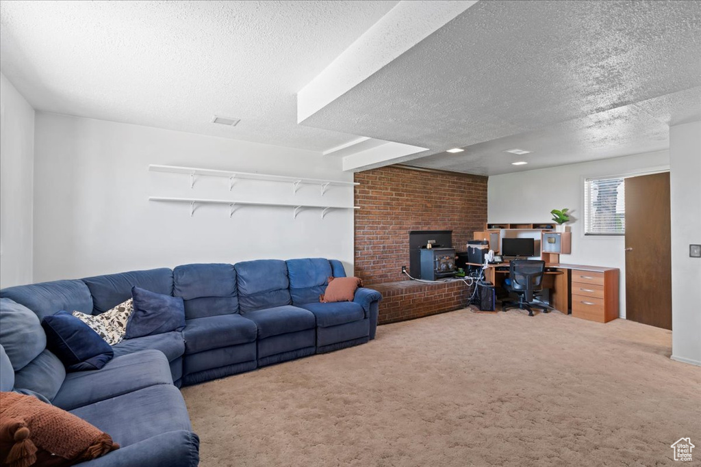 Carpeted living room featuring a textured ceiling, a desk, and a wood stove