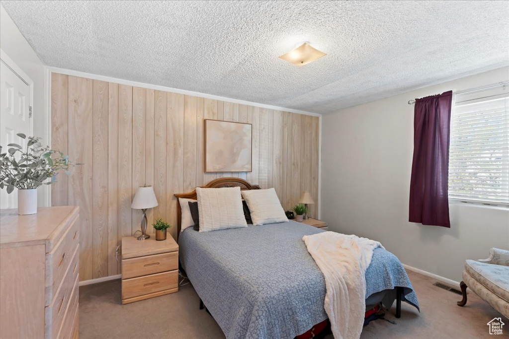 Carpeted bedroom with wooden walls, baseboards, and a textured ceiling