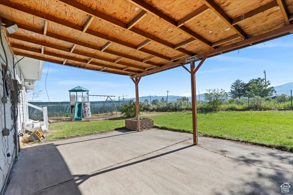 View of patio with a mountain view and a playground