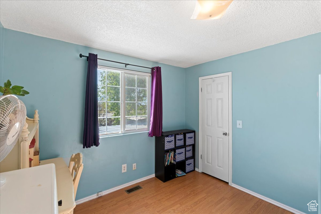 Office featuring wood finished floors, a textured ceiling, and baseboards