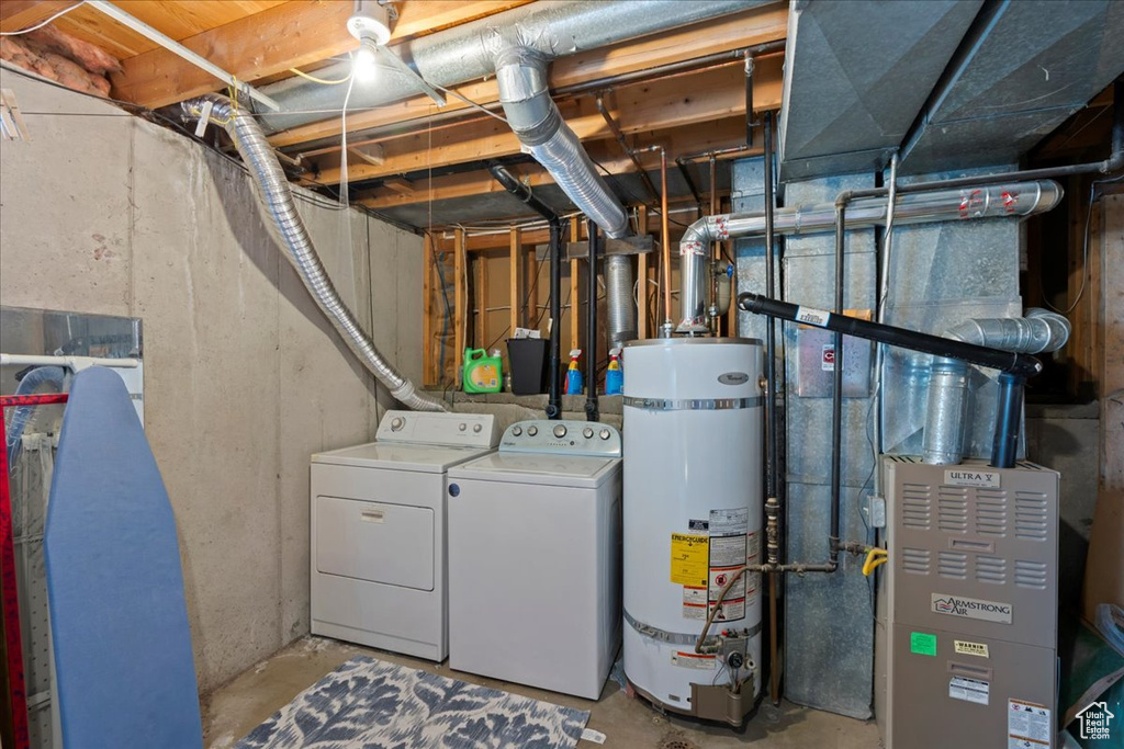 Unfinished below grade area featuring strapped water heater and washer and dryer