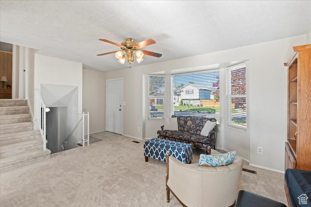 Sitting room featuring carpet, ceiling fan, baseboards, a textured ceiling, and an upstairs landing