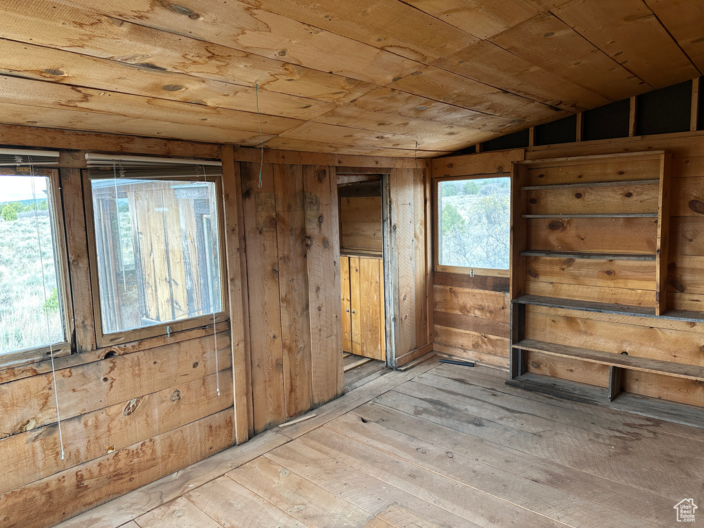 Spare room featuring wood ceiling, lofted ceiling, light wood-type flooring, and wood walls