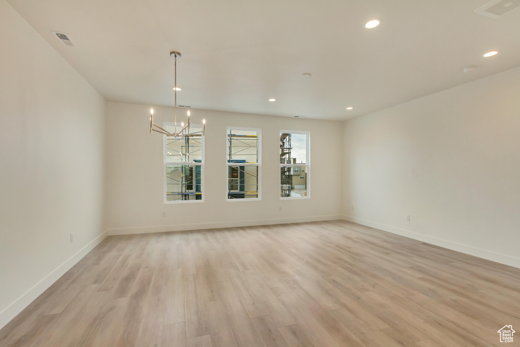 Spare room featuring a chandelier, light wood-style flooring, recessed lighting, and baseboards
