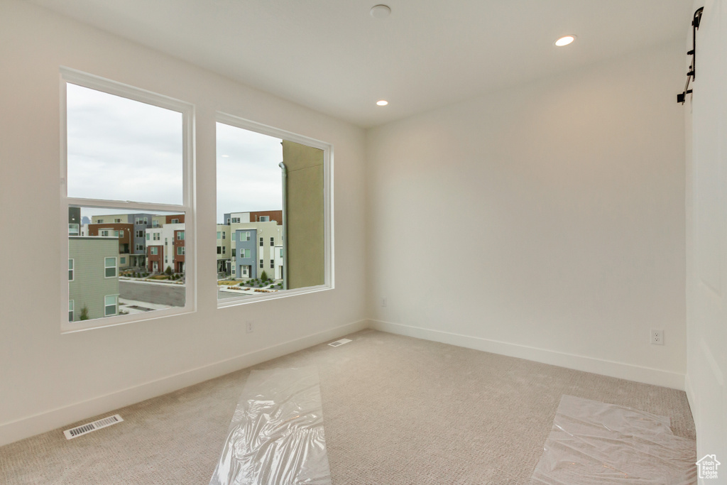 Carpeted spare room with a barn door, baseboards, and recessed lighting
