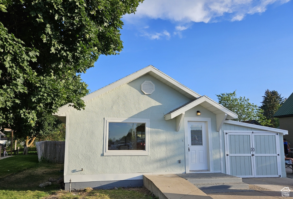 Bungalow-style home with fence and stucco siding