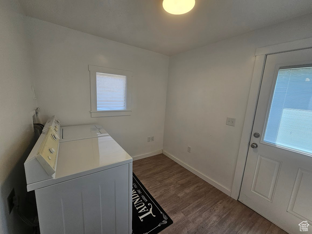 Laundry room with washer and dryer, healthy amount of natural light, dark wood-type flooring, and baseboards