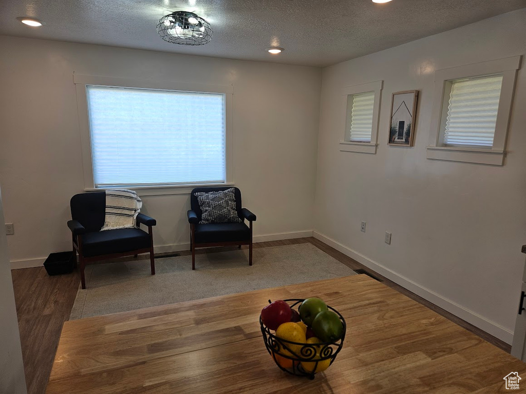 Sitting room featuring a textured ceiling, baseboards, and wood finished floors