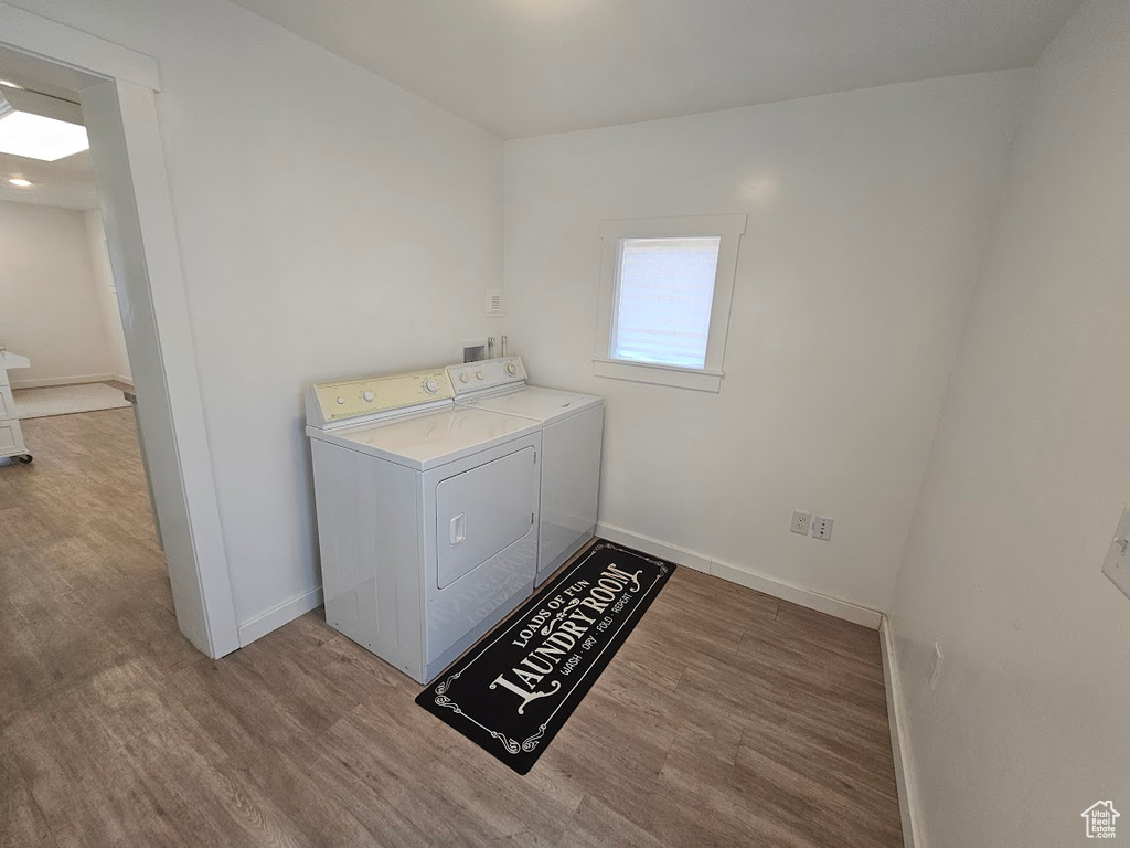 Laundry area featuring wood finished floors, independent washer and dryer, and baseboards