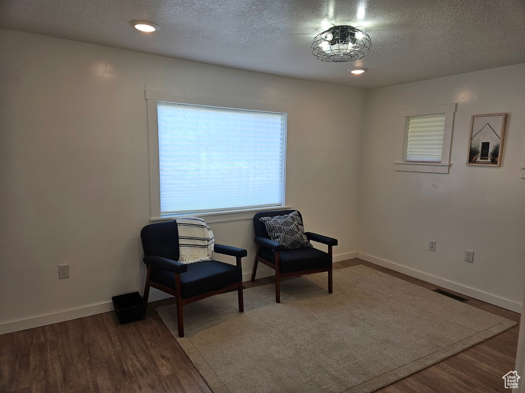 Living area featuring wood finished floors, a textured ceiling, and baseboards