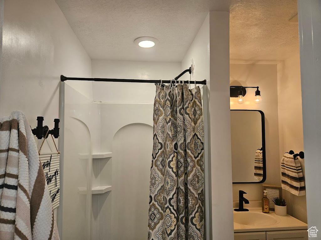 Full bathroom featuring a textured ceiling, a shower with shower curtain, and vanity