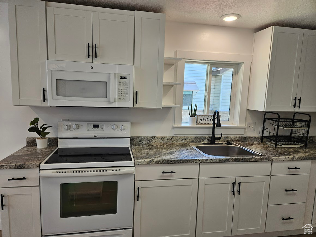 Kitchen with white appliances, a sink, white cabinets, a textured ceiling, and open shelves
