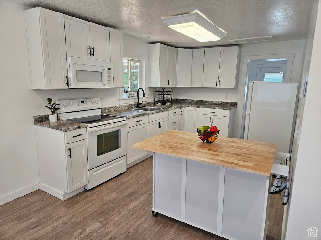 Kitchen featuring white appliances, a sink, light wood-style flooring, white cabinetry, and butcher block counters