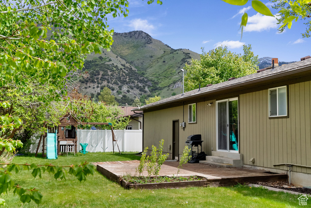 Rear view of house with a mountain view, a playground, and entry steps