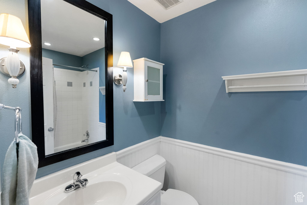 Full bathroom featuring a wainscoted wall, toilet, and vanity