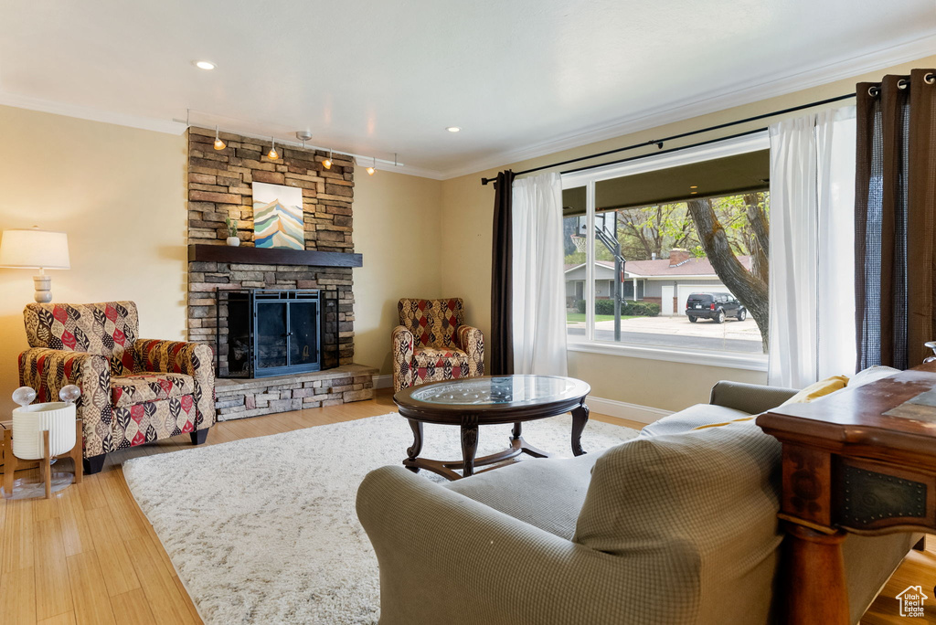 Living room with crown molding, a fireplace, wood finished floors, baseboards, and recessed lighting