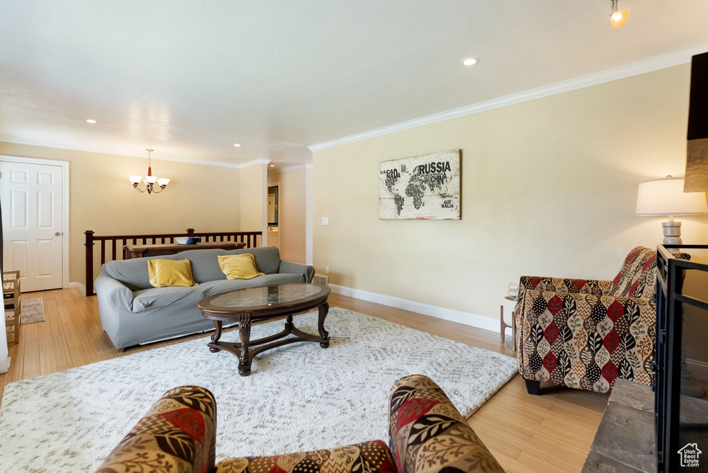 Living room with a chandelier, wood finished floors, ornamental molding, recessed lighting, and baseboards