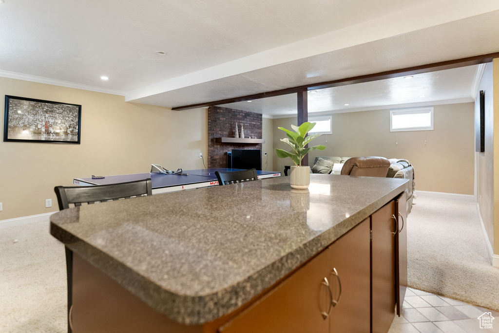Kitchen with light carpet, open floor plan, a kitchen island, baseboards, and a brick fireplace