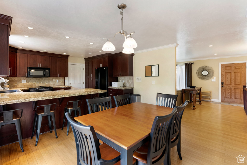 Dining space with recessed lighting, crown molding, and light wood-style floors
