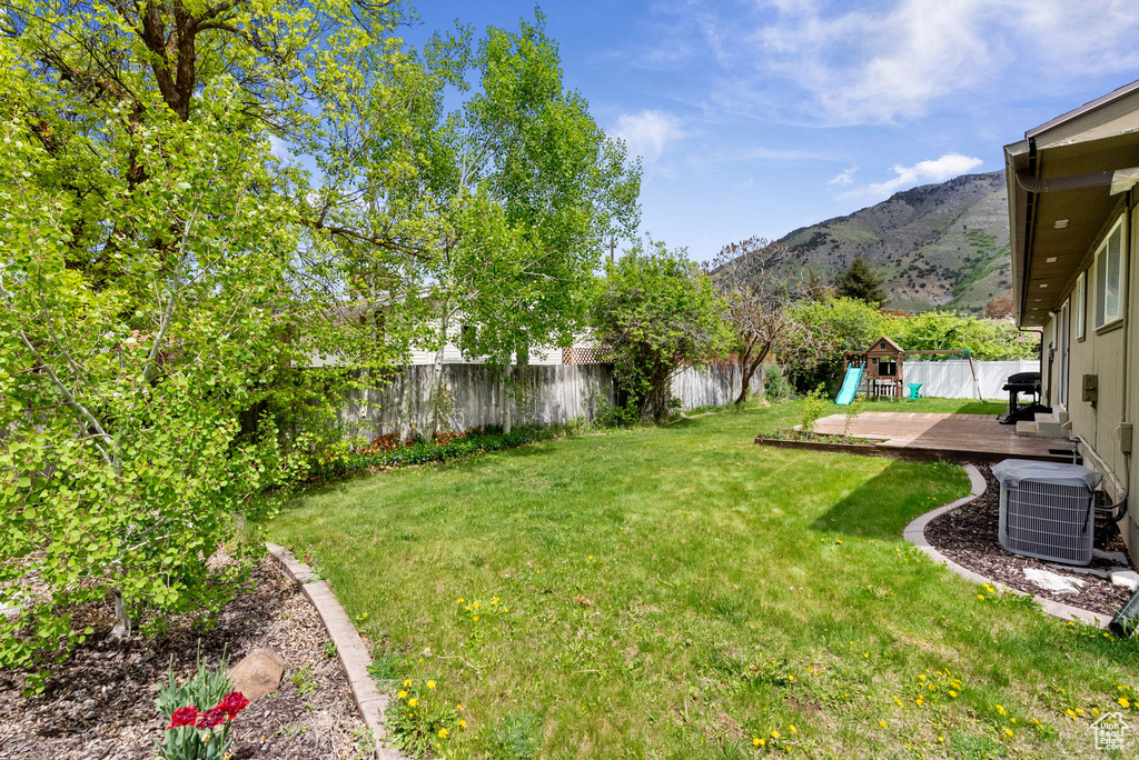 View of yard with central air condition unit and a deck with mountain view