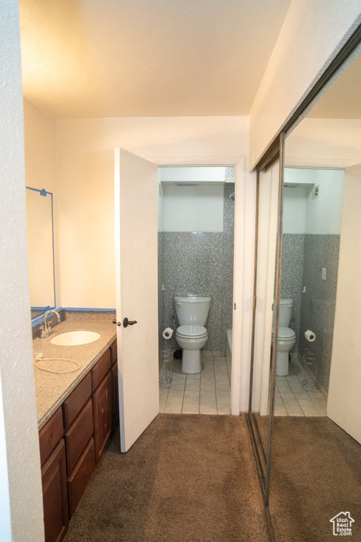 Full bathroom with toilet, vanity, tile patterned flooring, and tile walls