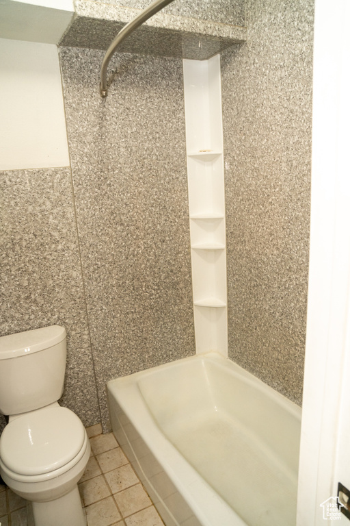 Bathroom featuring toilet, tile patterned floors, a shower, and tile walls