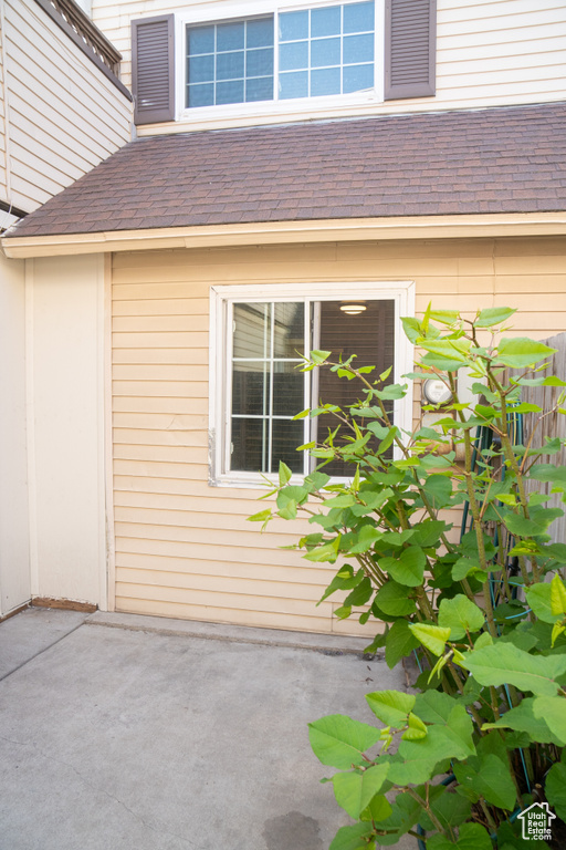 Property entrance with a shingled roof and a patio area