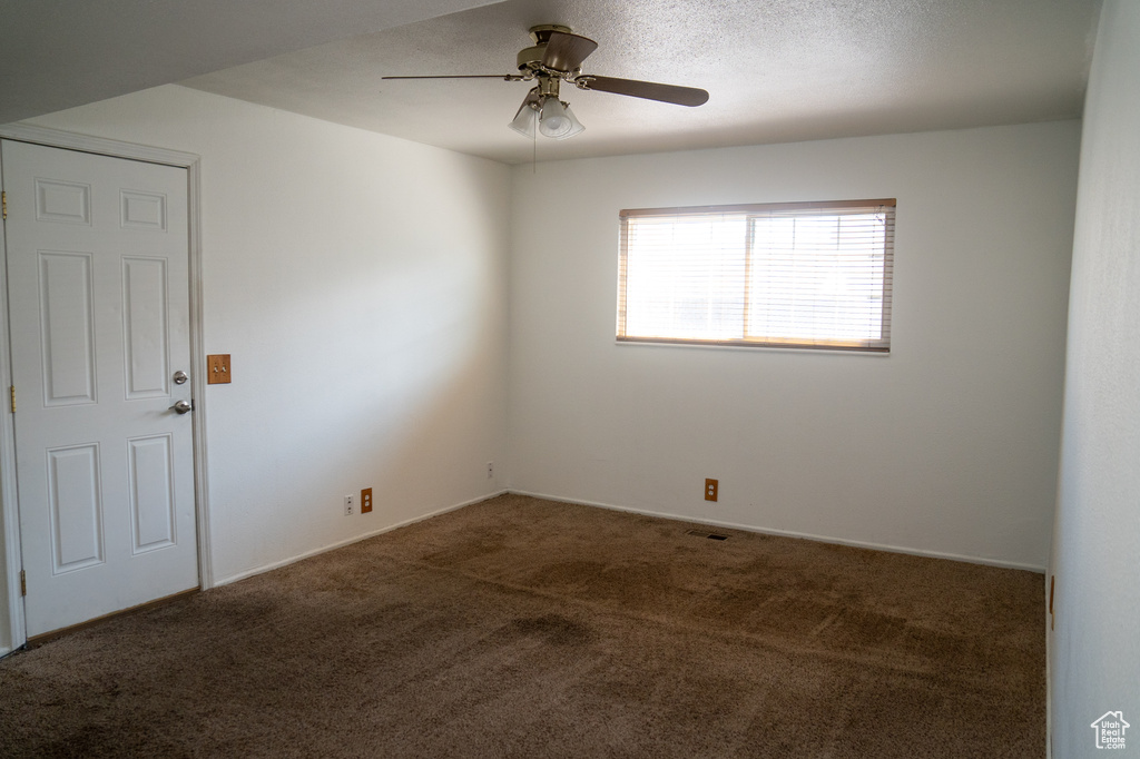 Carpeted spare room featuring a ceiling fan
