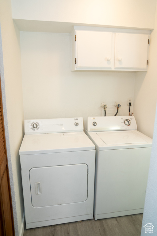 Washroom with cabinet space, separate washer and dryer, and wood finished floors