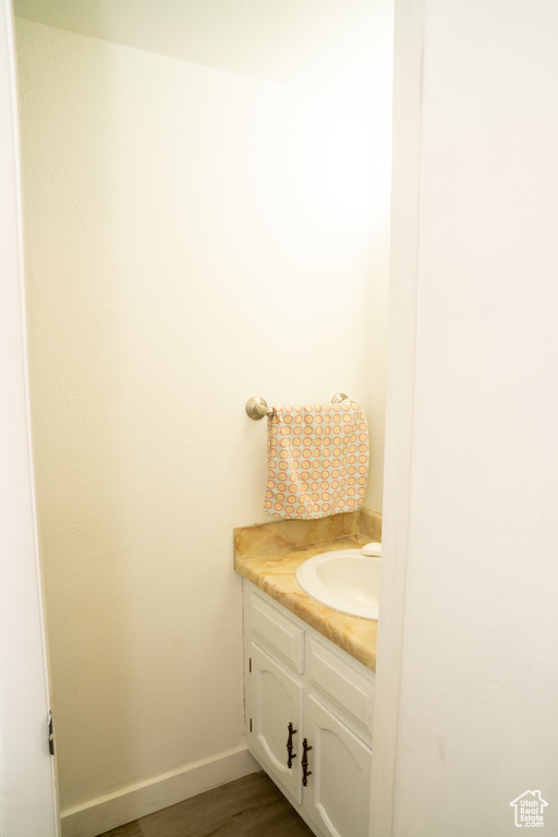 Bathroom with vanity, wood finished floors, and baseboards