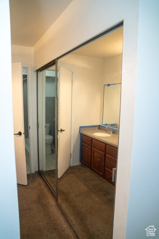 Bathroom with toilet, vanity, and carpet flooring