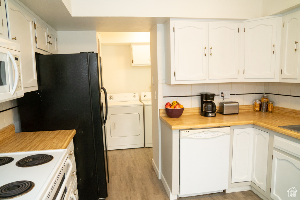 Kitchen with white appliances, washer and dryer, and tasteful backsplash