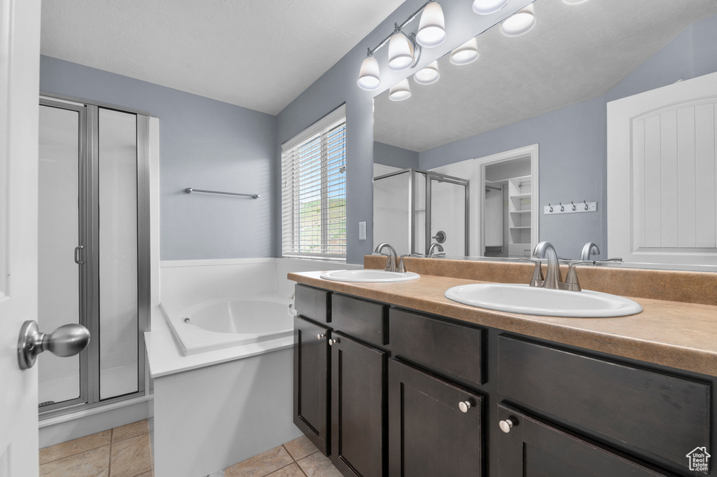 Bathroom featuring a stall shower, double vanity, and a bath