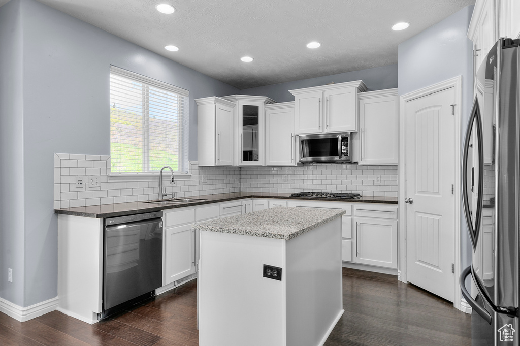 Kitchen with appliances with stainless steel finishes, a sink, dark wood-style floors, white cabinetry, and recessed lighting