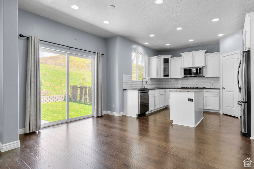 Kitchen featuring appliances with stainless steel finishes, a sink, a center island, backsplash, and recessed lighting