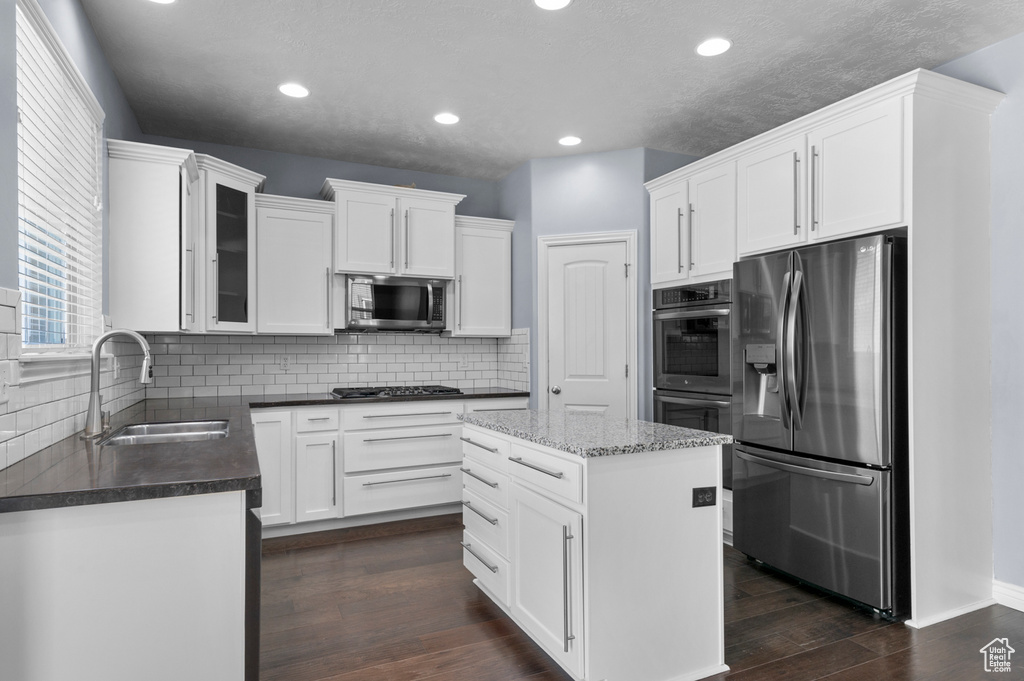 Kitchen featuring appliances with stainless steel finishes, a sink, white cabinets, backsplash, and recessed lighting